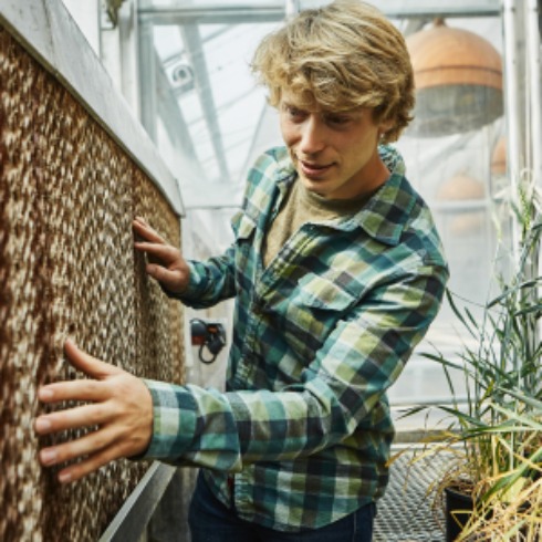 Spencer Fitz-Gerald, part of a three-student team whose greenhouse design won a top place at an international competition, examines an evaporation pad in the Plant Growth Center at MSU on Aug. 31, 2021