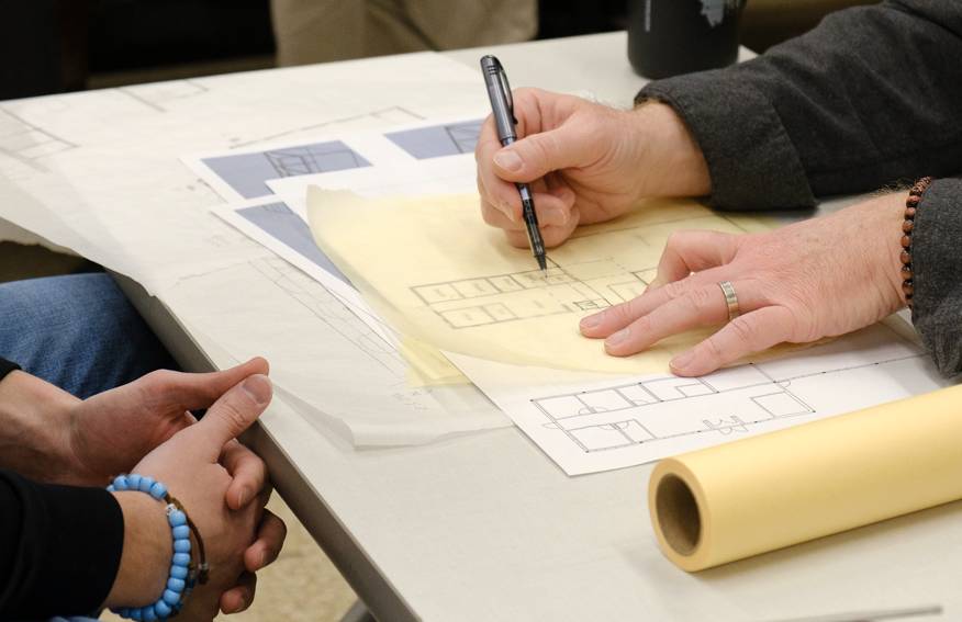 Two individuals drawing an overlay on floorplan