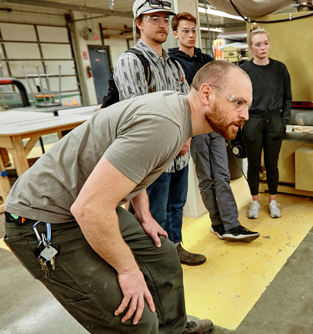 Sean Clearwater, front, shows students how to use a CNC router, which can be used to make a wide variety of models and other objects.